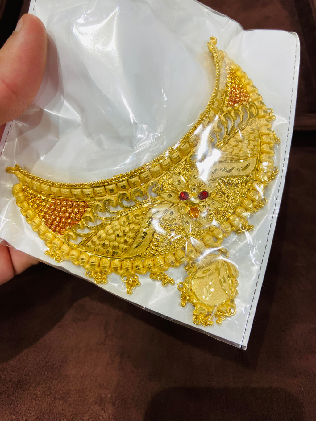 Gold necklace on a white card held by a hand