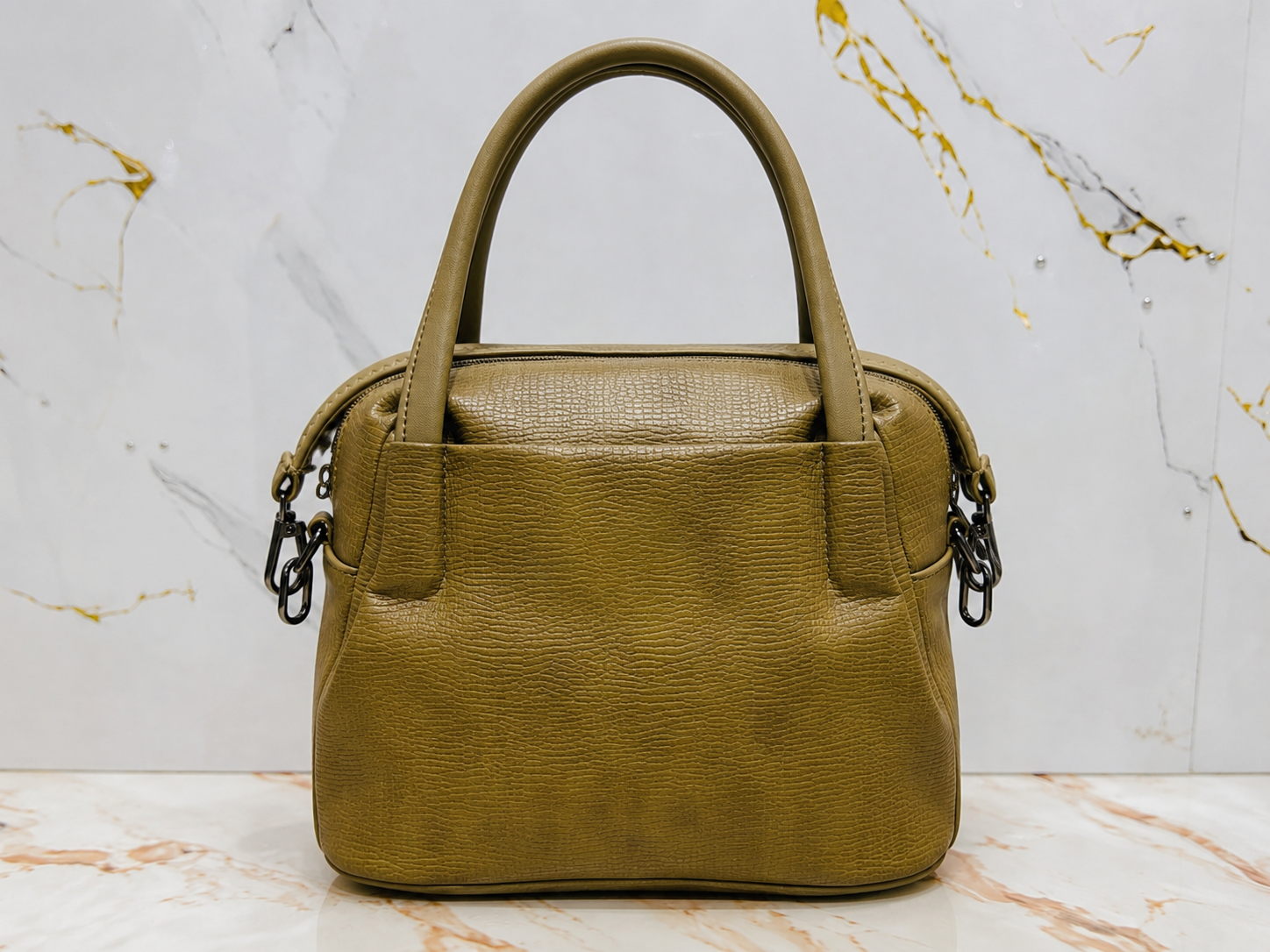 Green handbag on a marble surface with a white background
