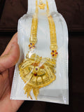 Gold long set with pendant on a white card held by a hand