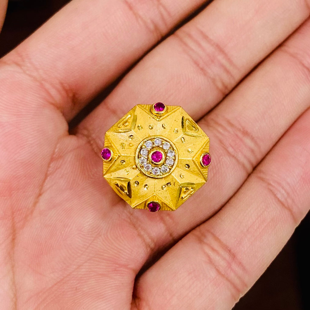 Gold ring with red gemstones held in a hand