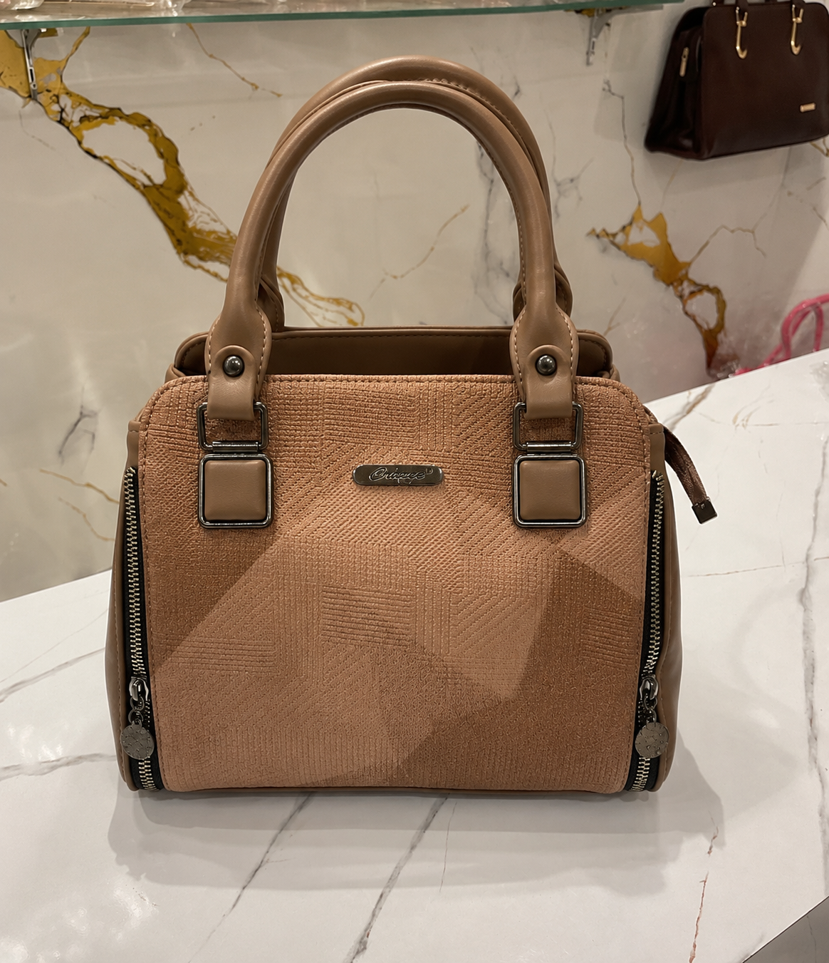 Brown handbag with gold accents on a marble surface