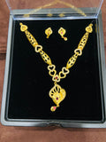 Gold necklace and earrings set in a clear display case on a wooden surface