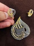 Gold and diamond earrings on a brown surface with a hand holding one earring.