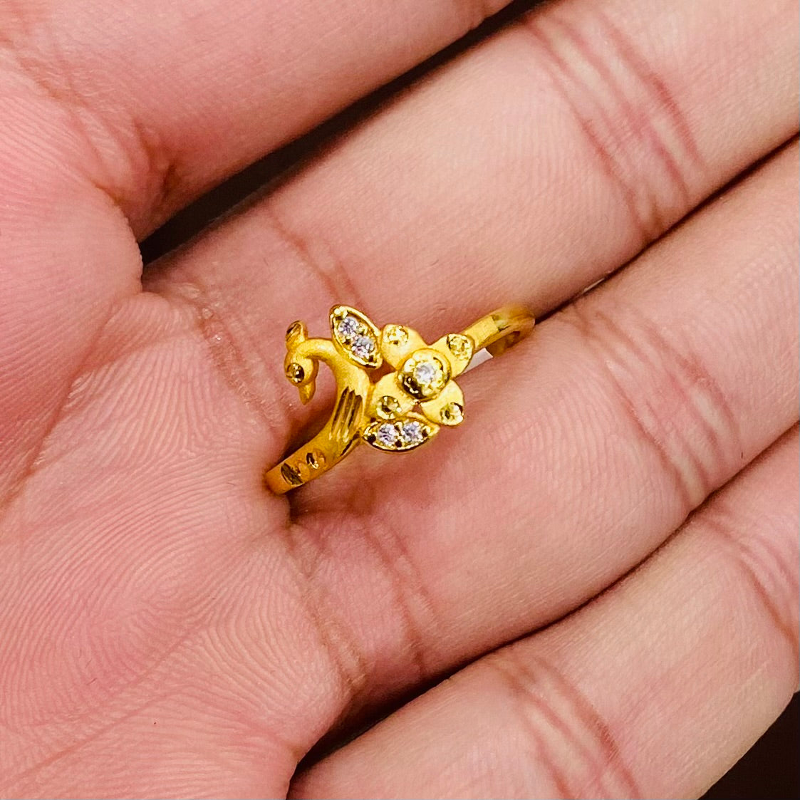 Gold ring with a peacock design on a person's hand