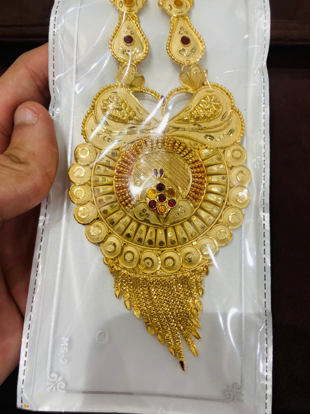 Gold necklace with intricate design on a white card