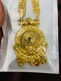 Gold necklace with intricate design and red gemstones on a white card