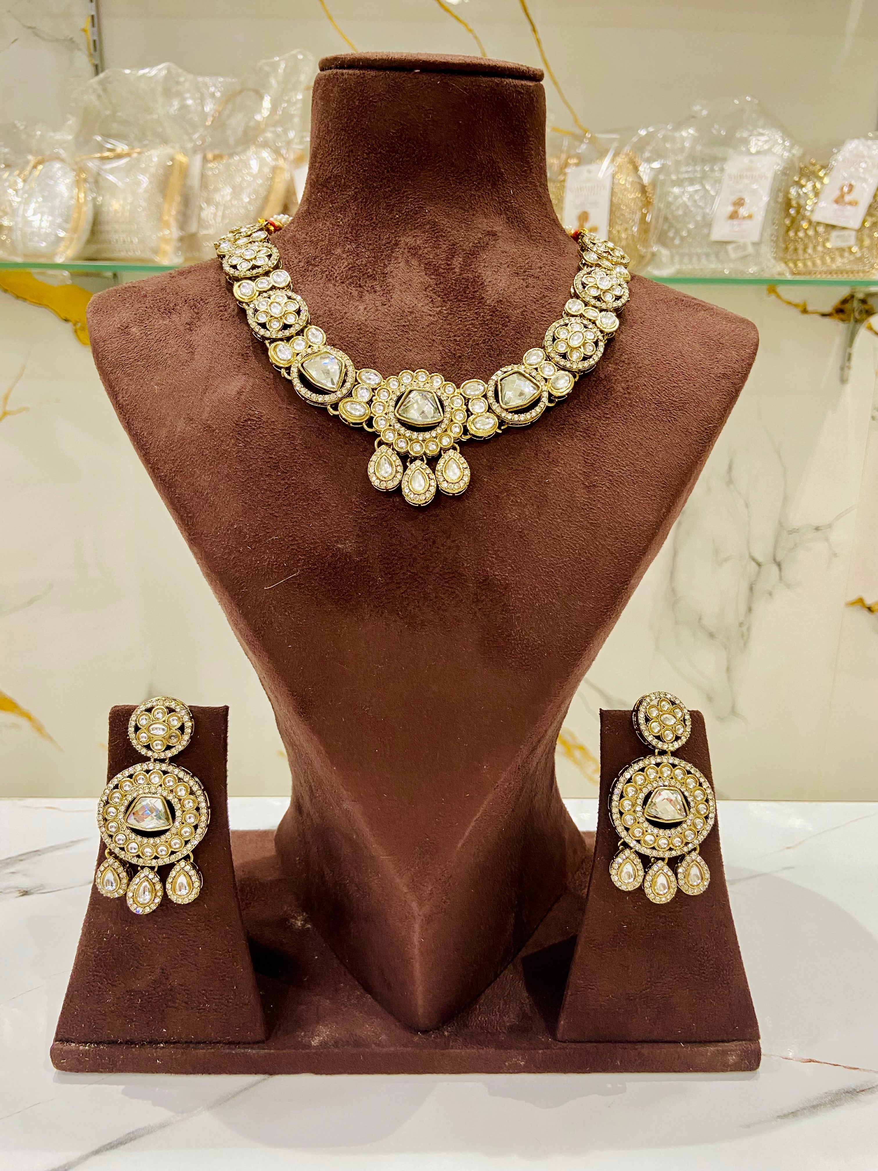 Jewelry set with necklace and earrings on a brown velvet stand.