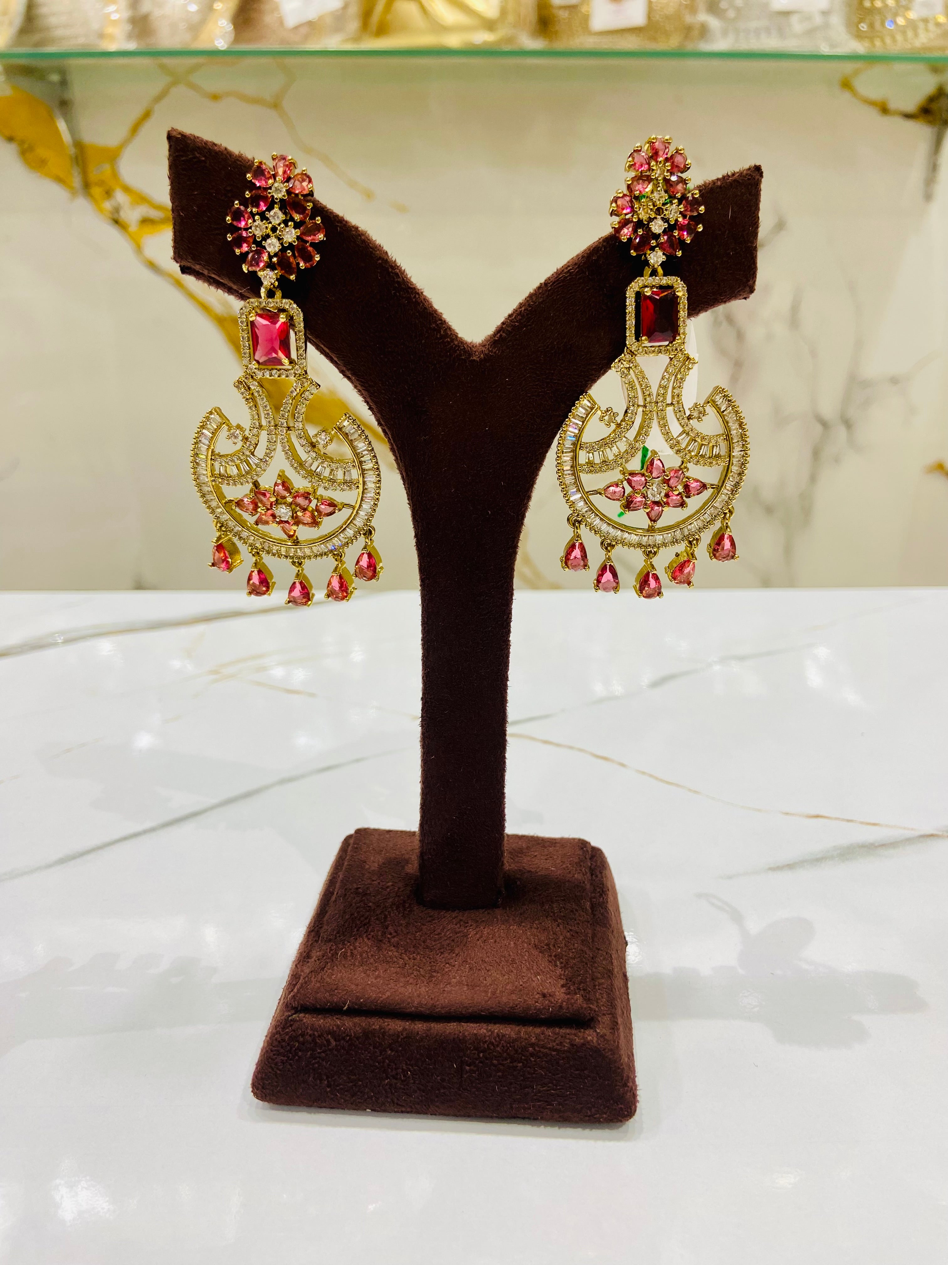 Pair of ornate earrings on a brown velvet stand with a marble background