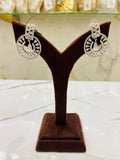 Pair of silver hoop earrings on a brown velvet stand with a blurred background.