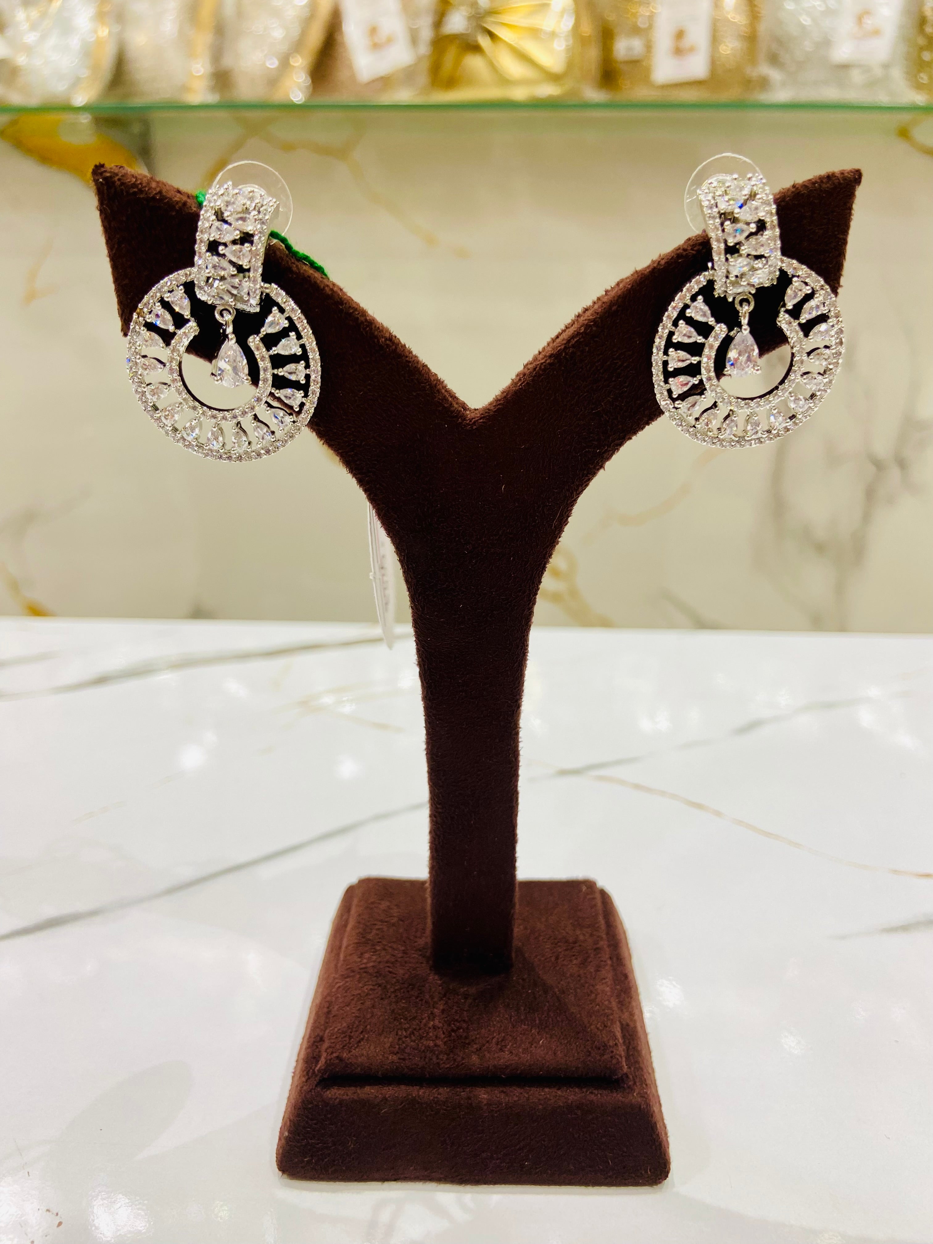 Pair of silver hoop earrings on a brown velvet stand with a blurred background.
