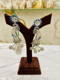 Pair of silver earrings with blue stones on a brown jewelry stand.