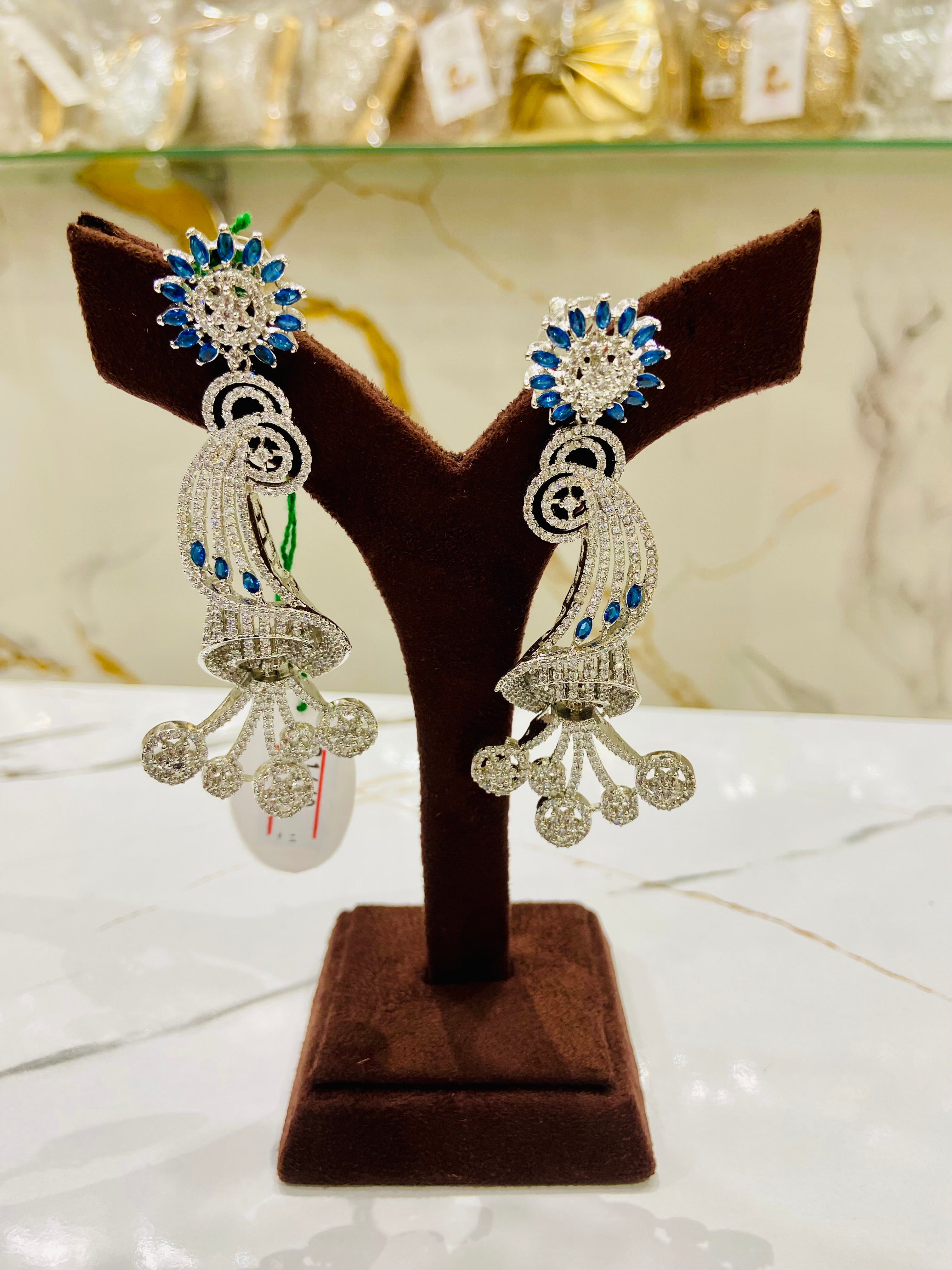 Pair of silver earrings with blue stones on a brown jewelry stand.