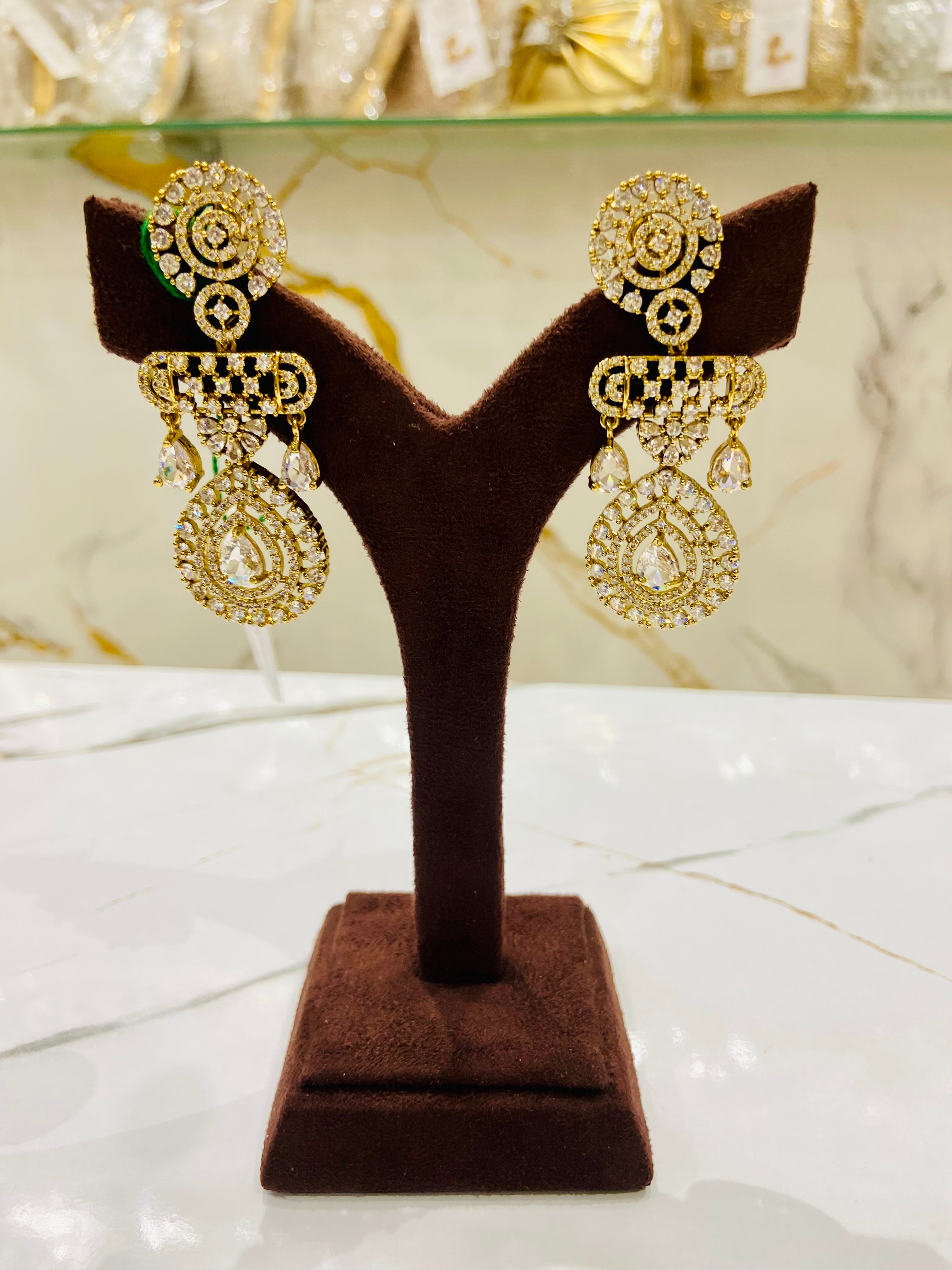 Gold earrings on a brown velvet stand with a marble background