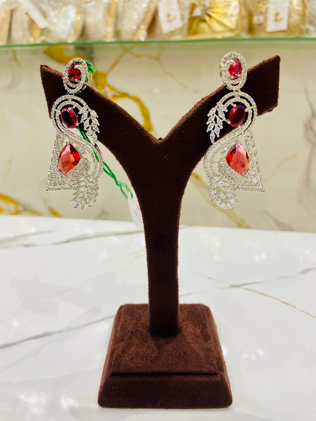 Pair of earrings on a brown velvet display stand with a blurred background