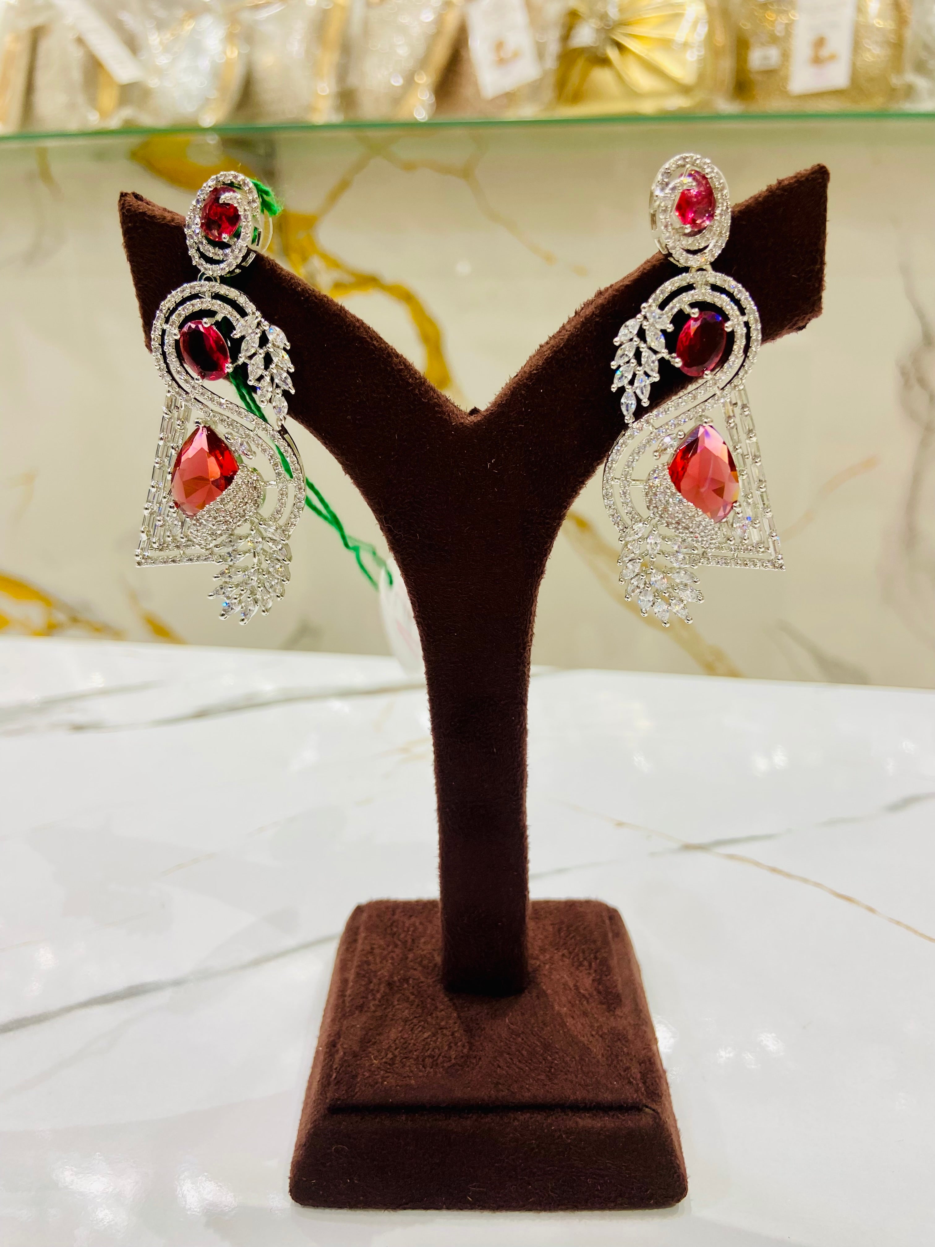 Pair of earrings on a brown velvet display stand with a blurred background
