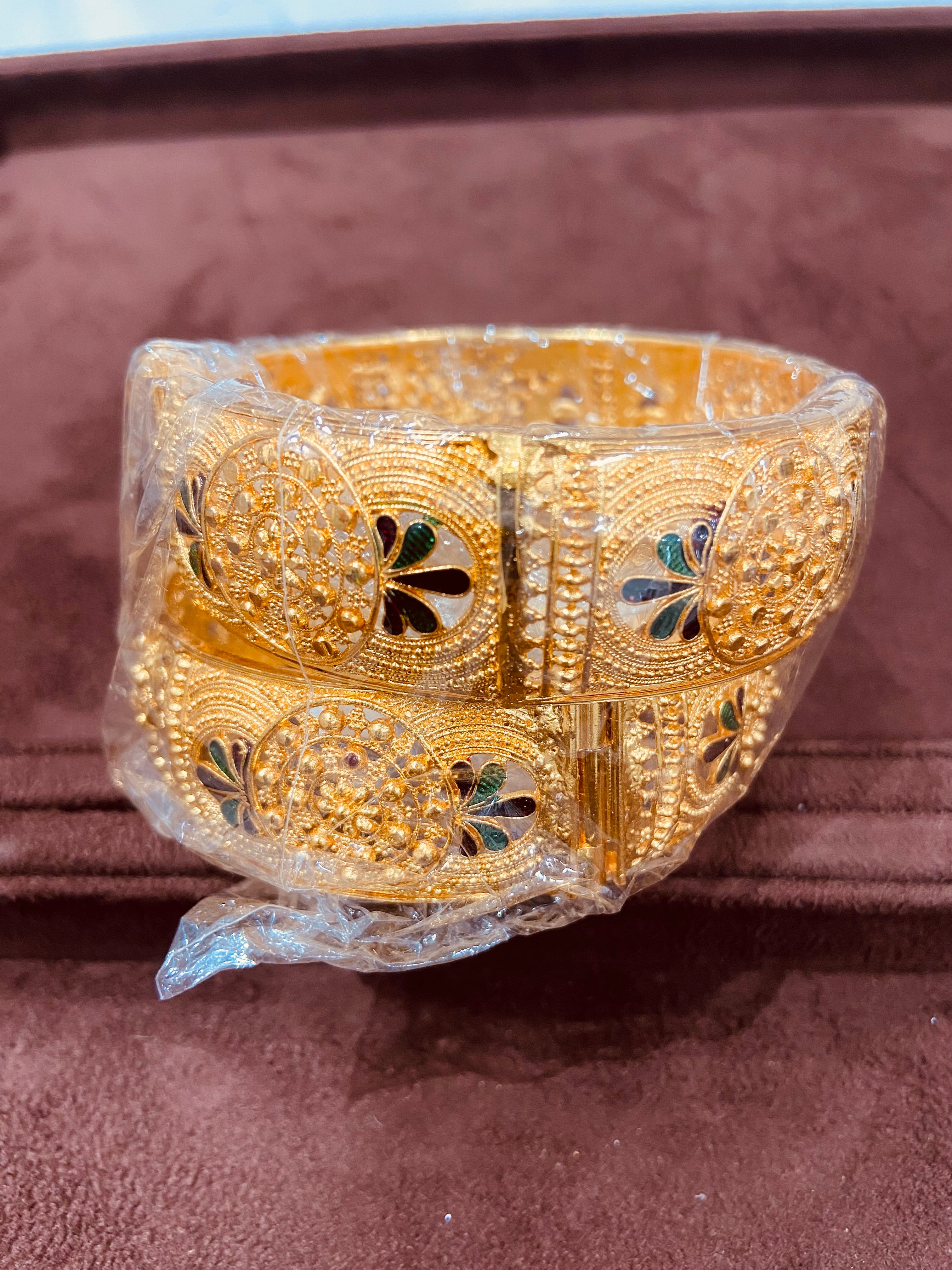 Gold bracelet with intricate designs on a brown surface