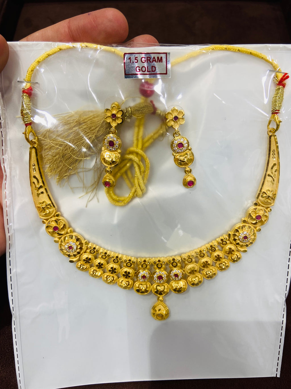Gold necklace and earrings set on a white card with gold tassels.