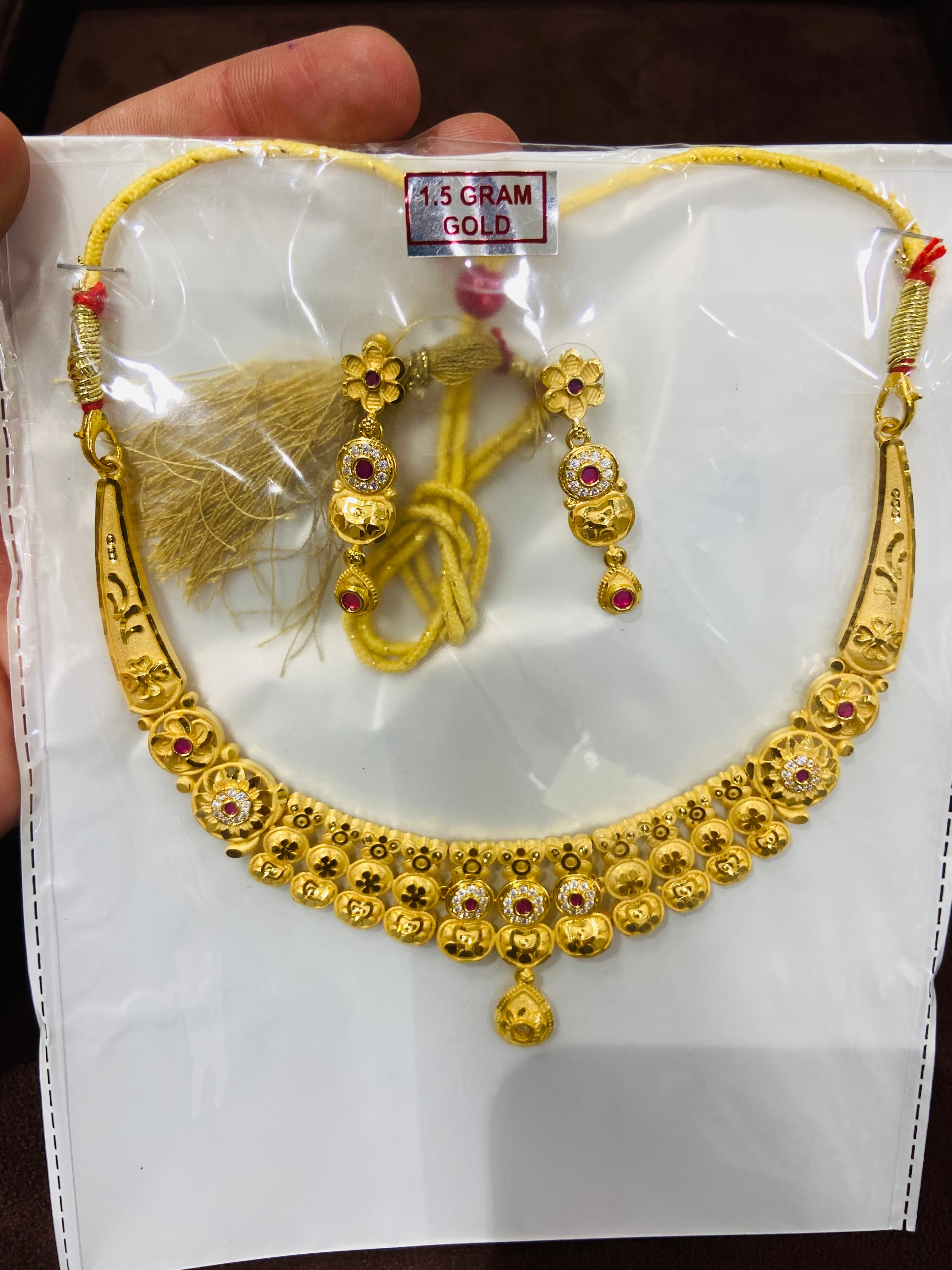 Gold necklace and earrings set on a white card with gold tassels.