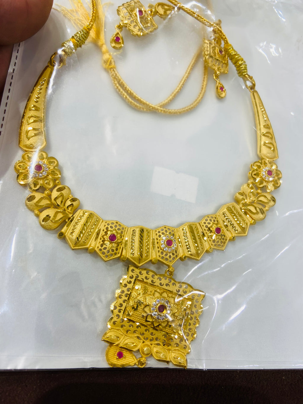 Gold necklace with intricate designs on a white background