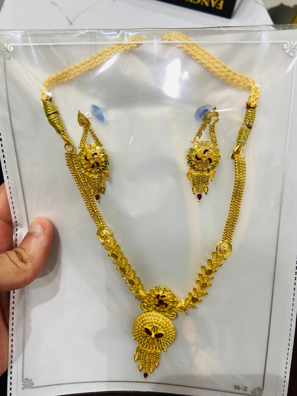 Gold necklace and earrings on a white card