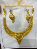 Gold necklace and earrings set on a white background