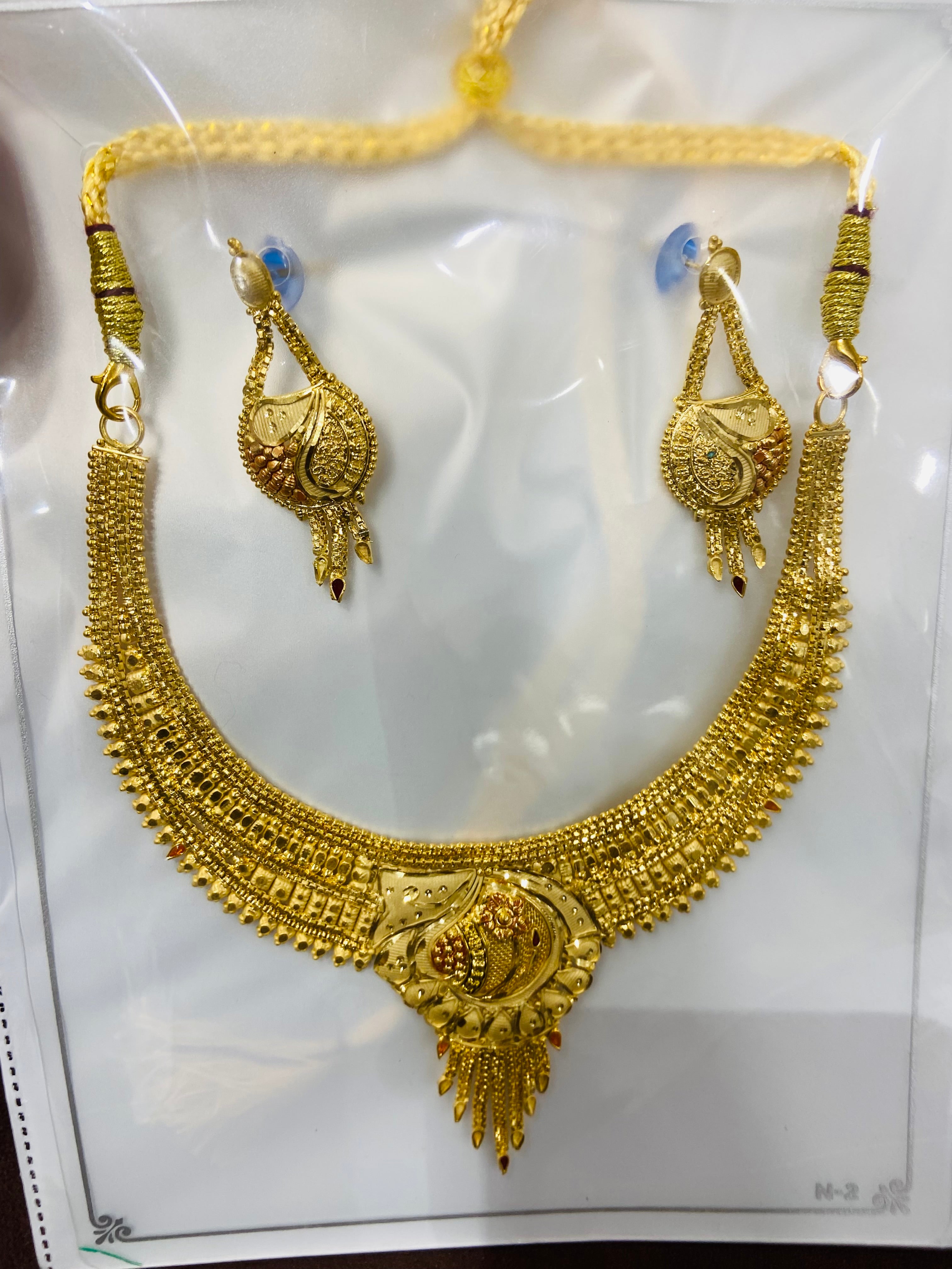 Gold necklace and earrings set on a white background