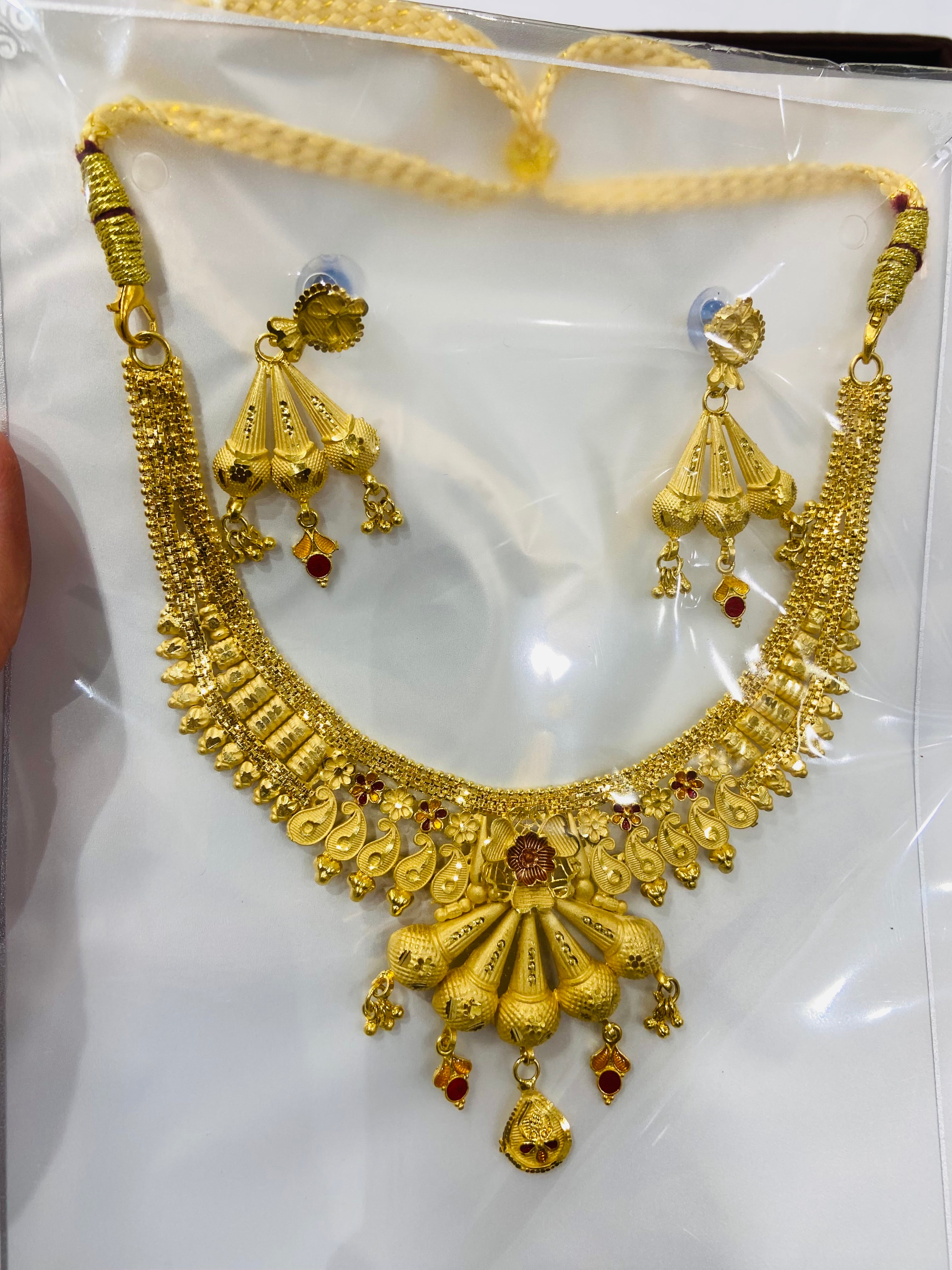 Gold necklace and earrings set on a white card