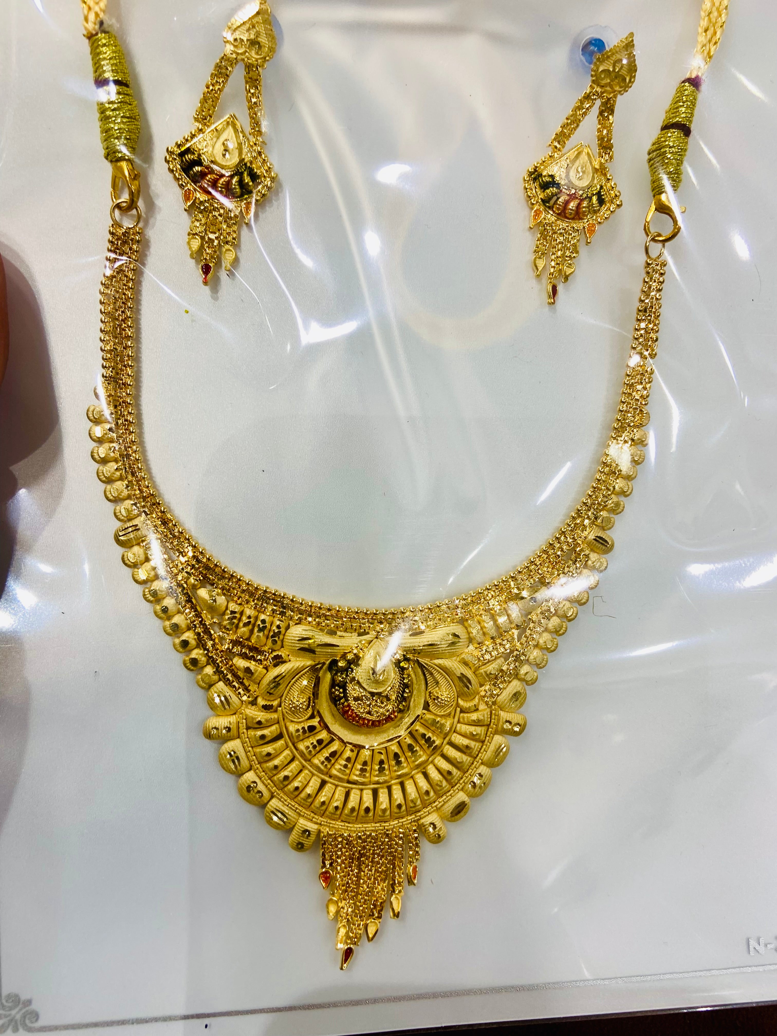 Gold necklace with matching earrings on a white background