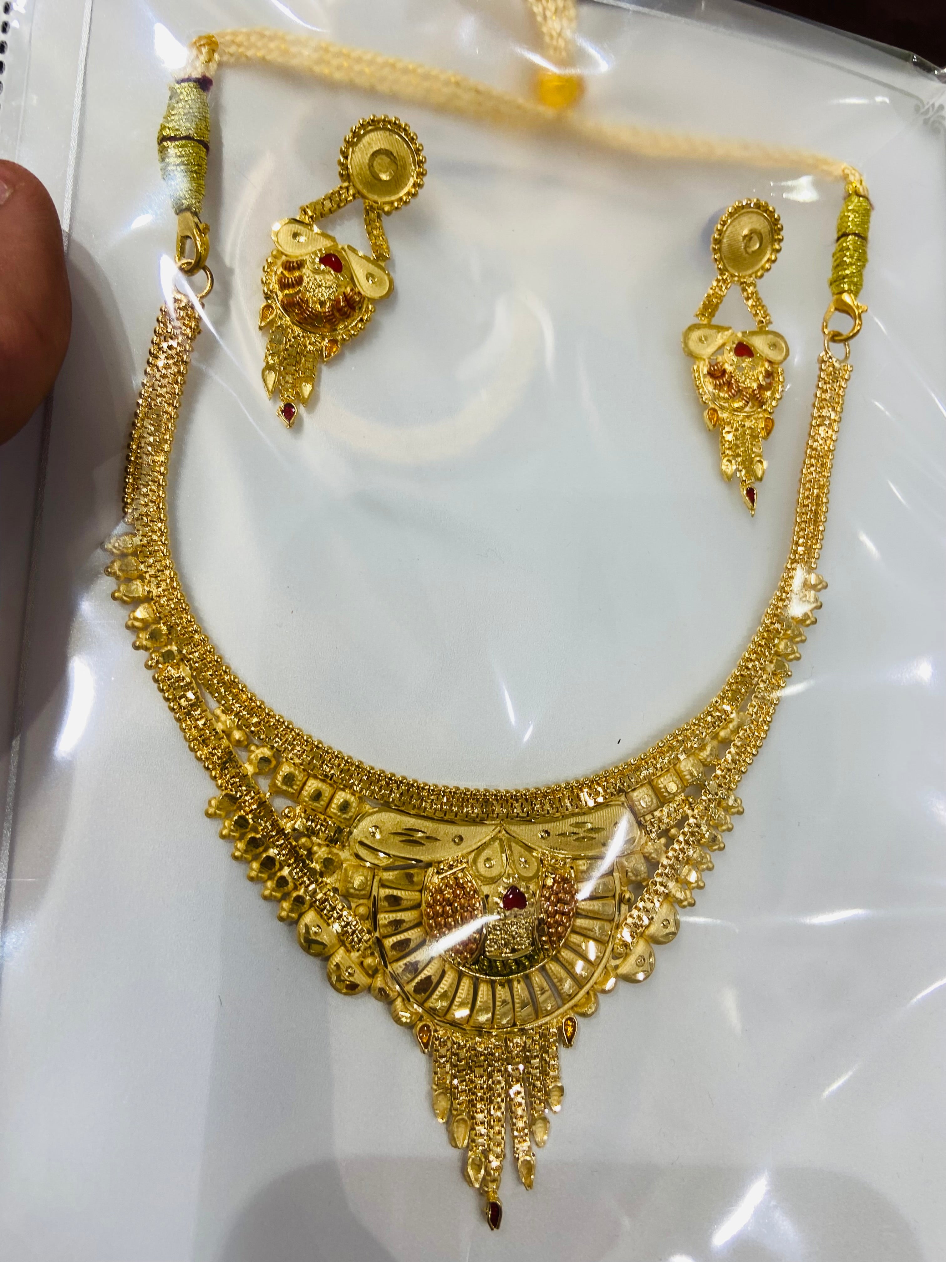 Gold necklace and earrings set on a white card