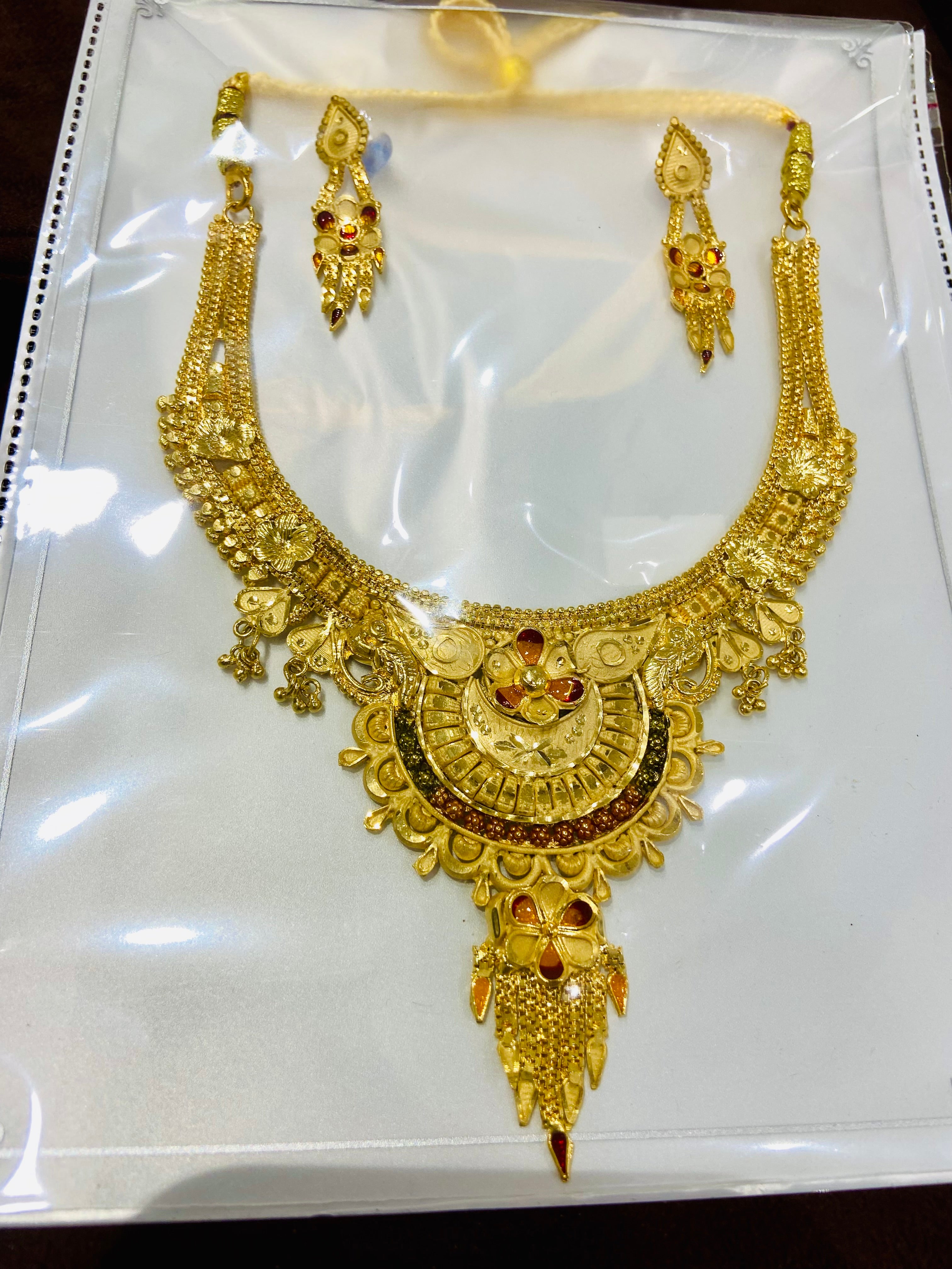 Gold necklace and earrings set on a white background