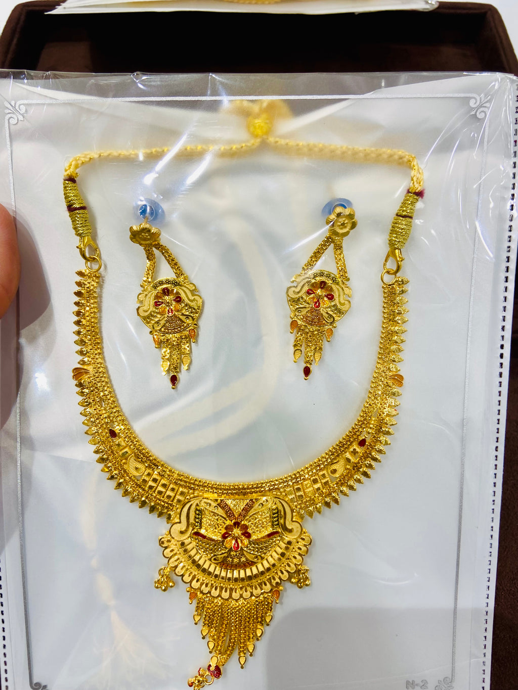 Gold necklace and earrings set on a white card