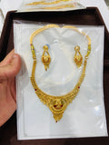 Gold necklace and earrings set on a card held by a hand