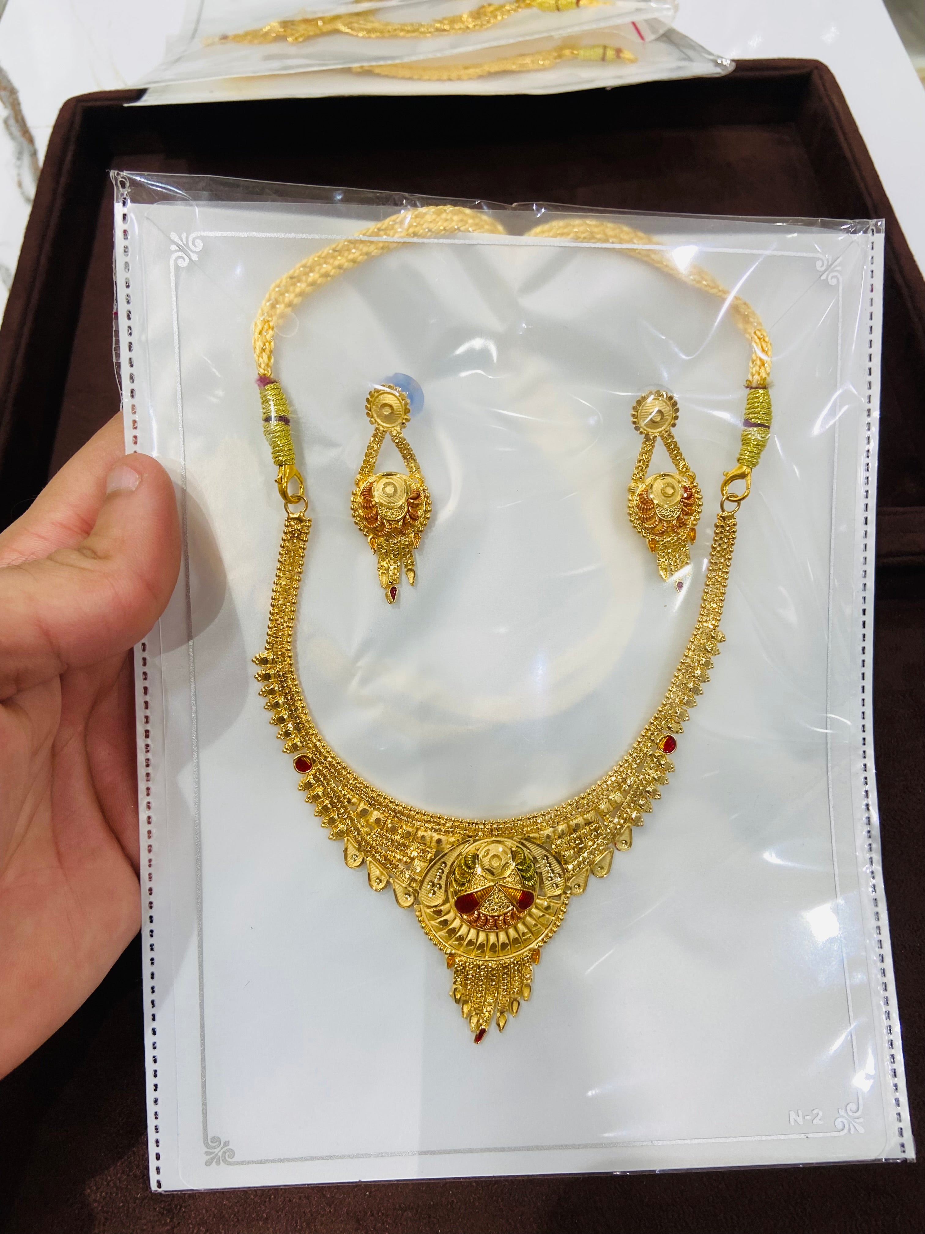 Gold necklace and earrings set on a card held by a hand