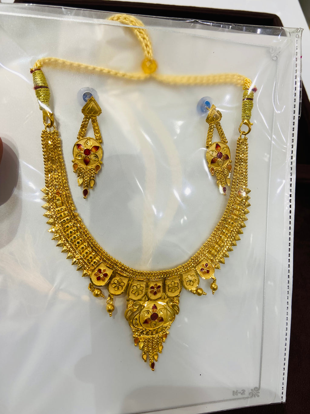 Gold necklace with intricate designs on a white background