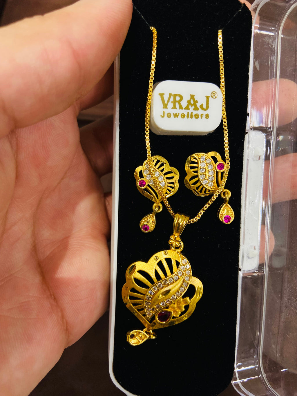 Gold necklace with pendant on a display card with branding.
