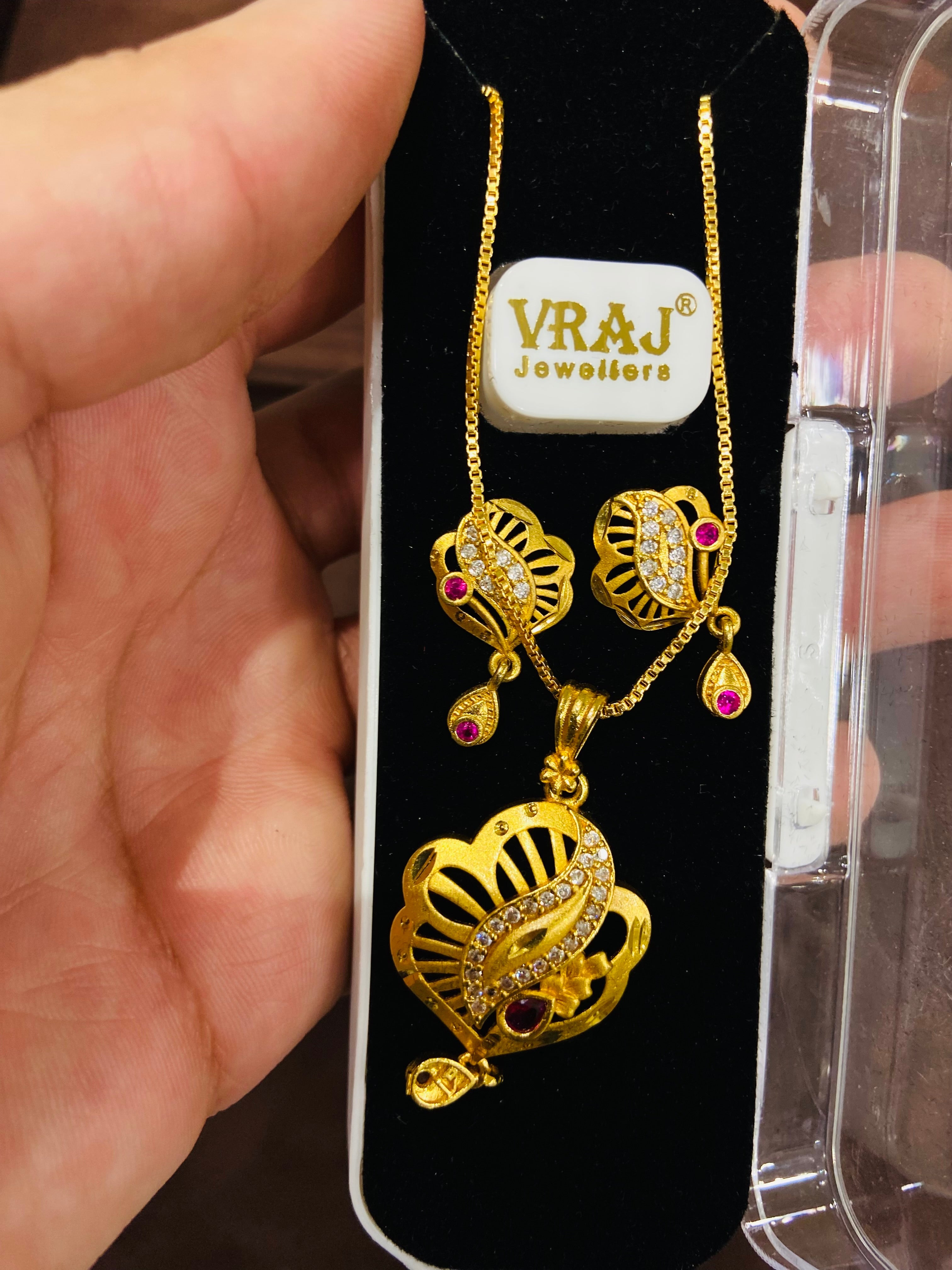Gold necklace with pendant on a display card with branding.