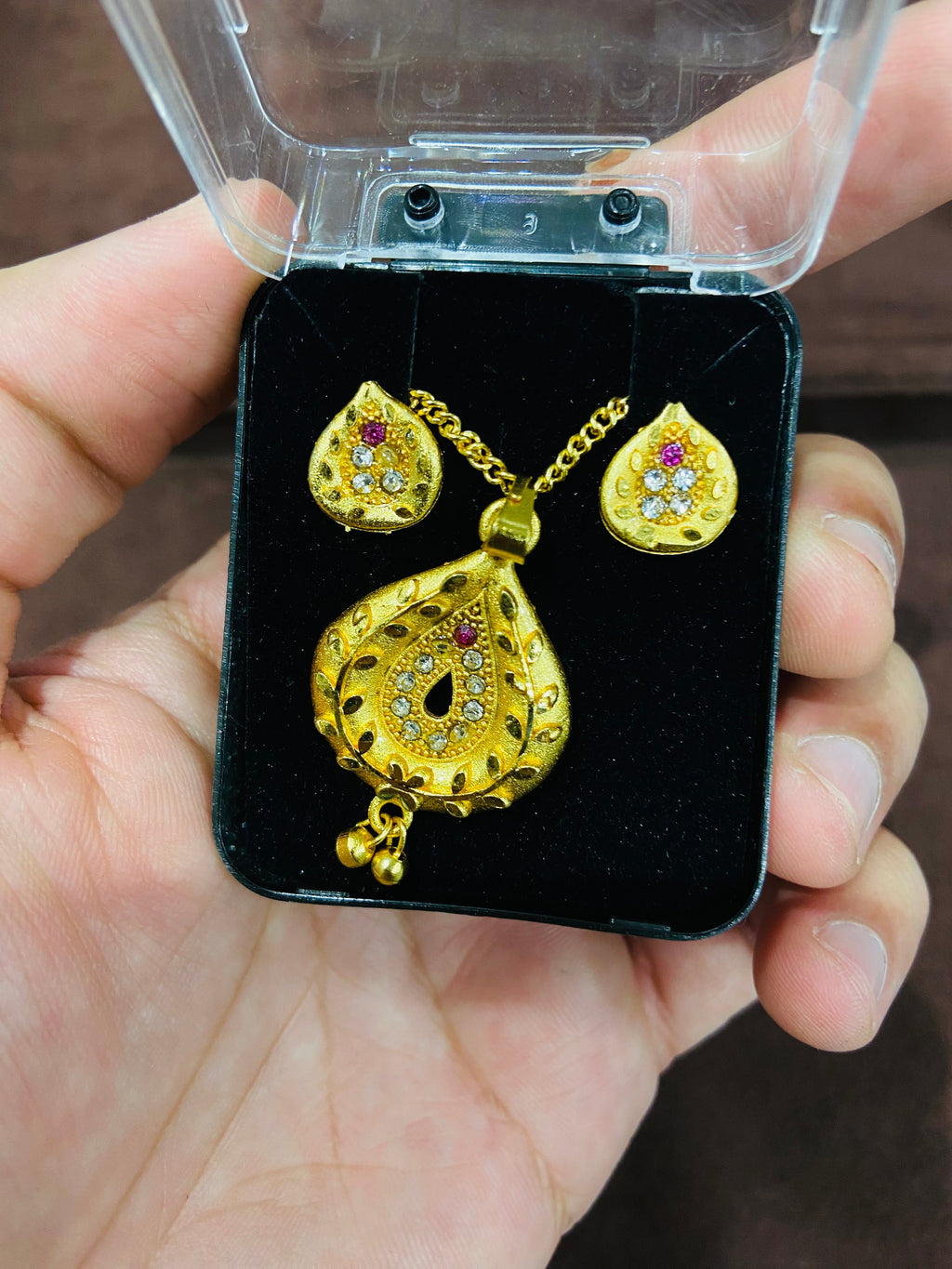 Gold jewelry set with heart design held in a hand