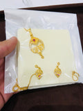 Gold necklace with red gemstones on a white card held by a hand.