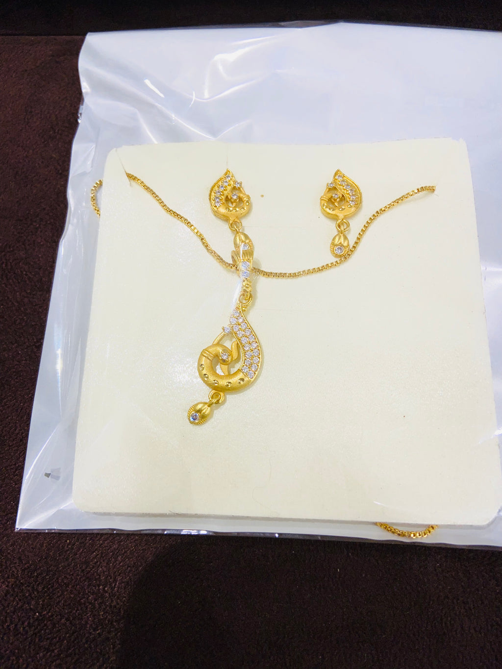 Gold necklace and earrings on a white card with a clear plastic cover