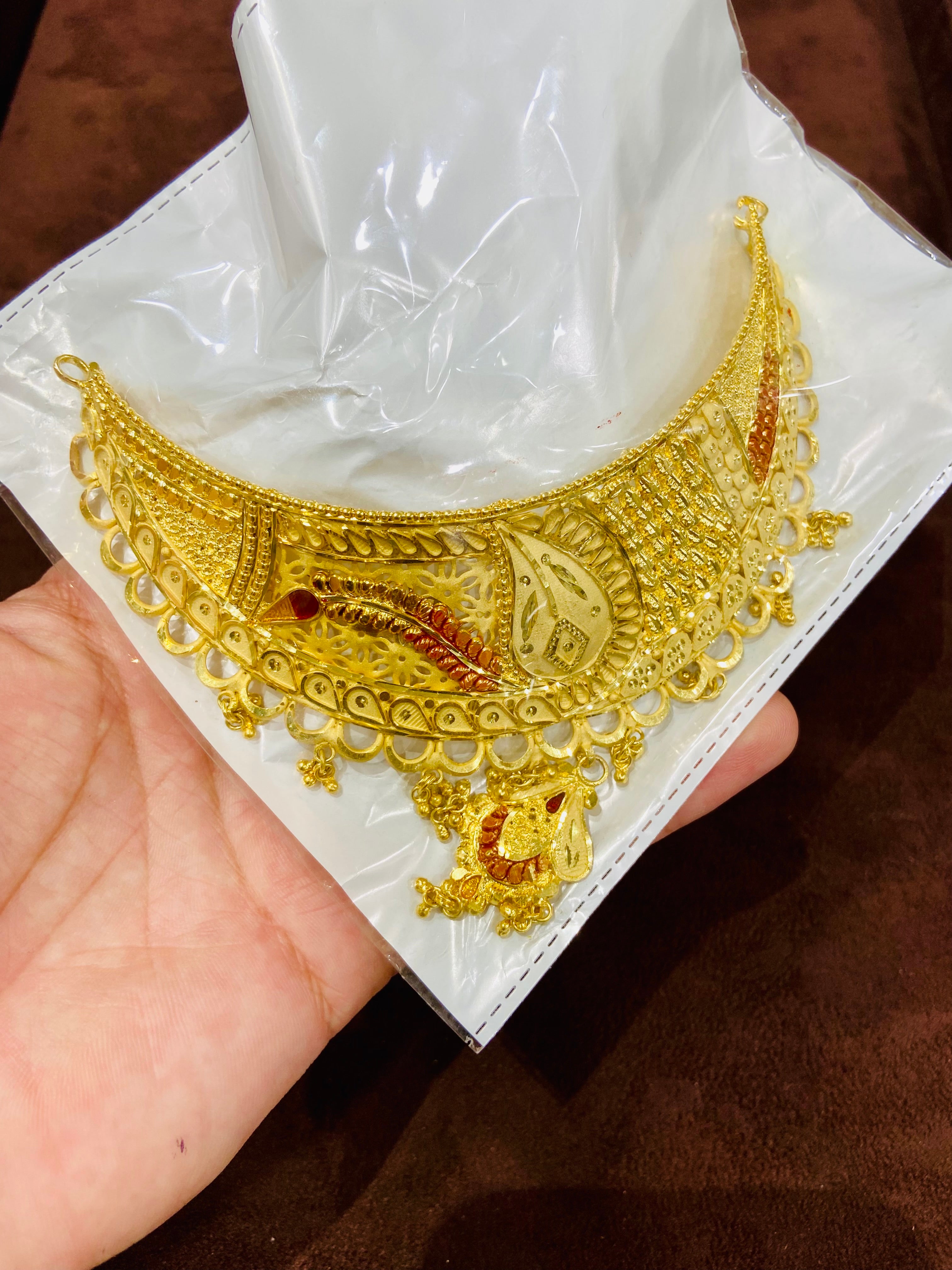 Gold necklace on a white box held by a hand