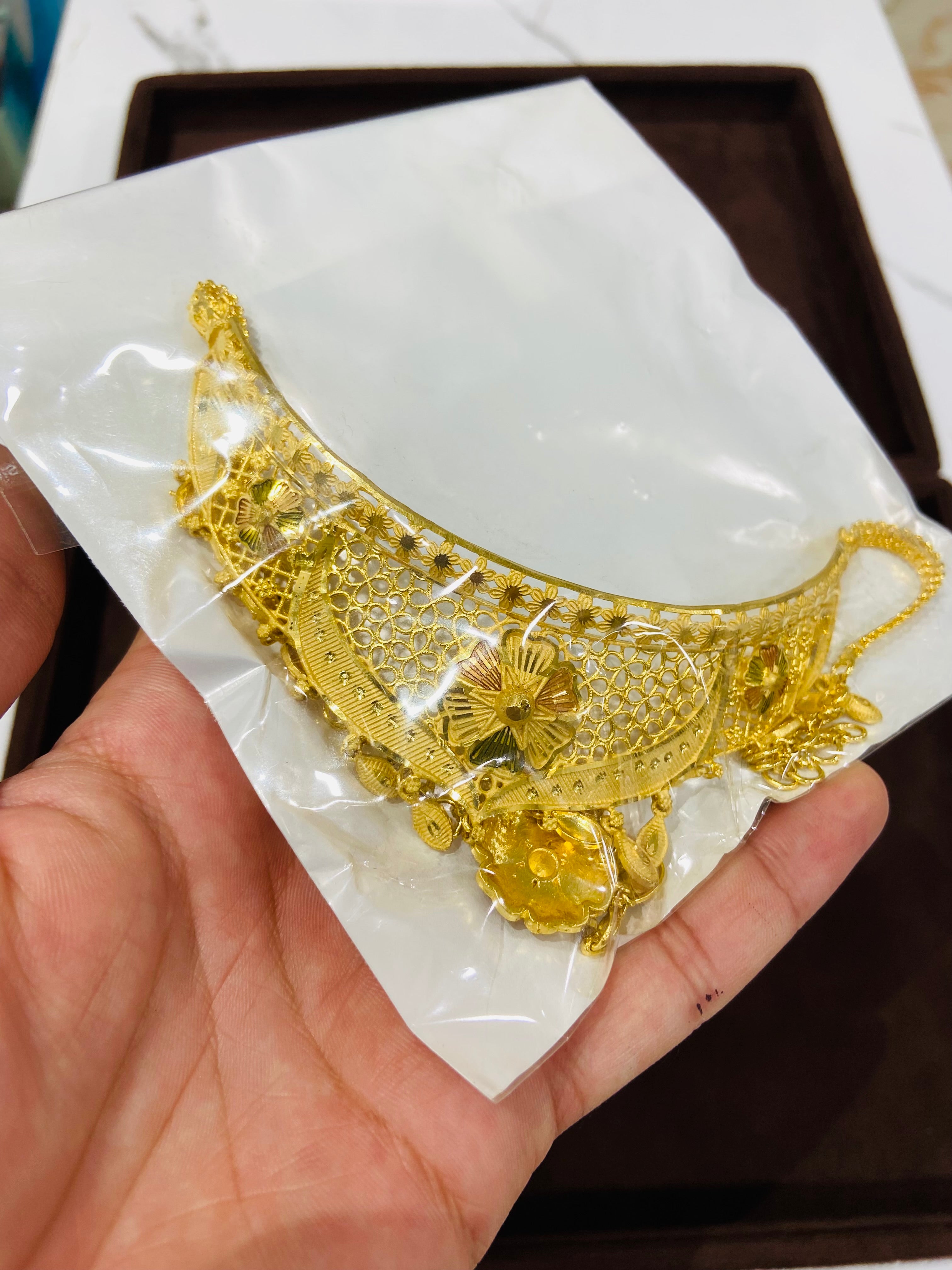 Gold necklace on a white card held by a hand