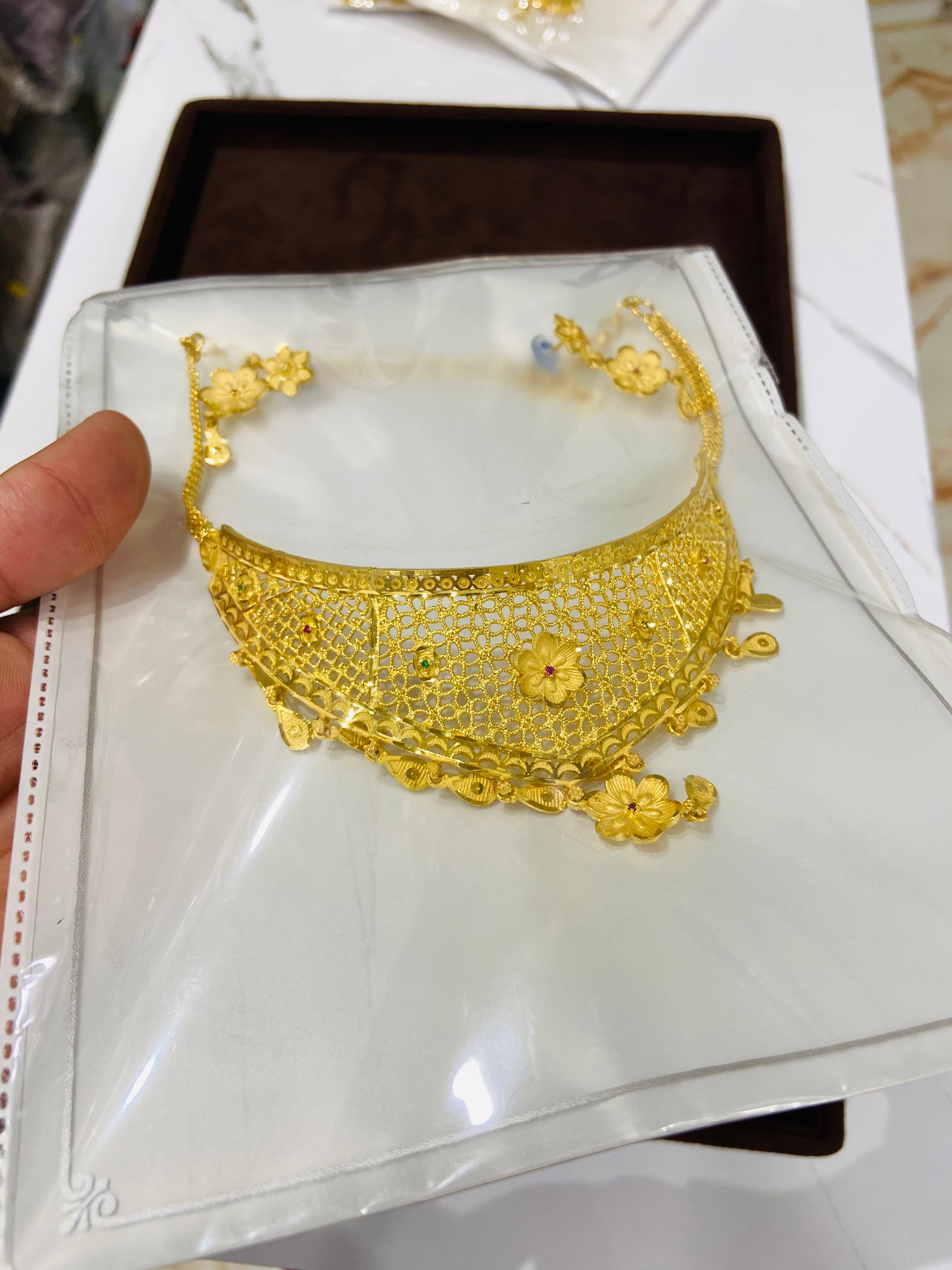 Gold necklace on a white card with a brown box in the background