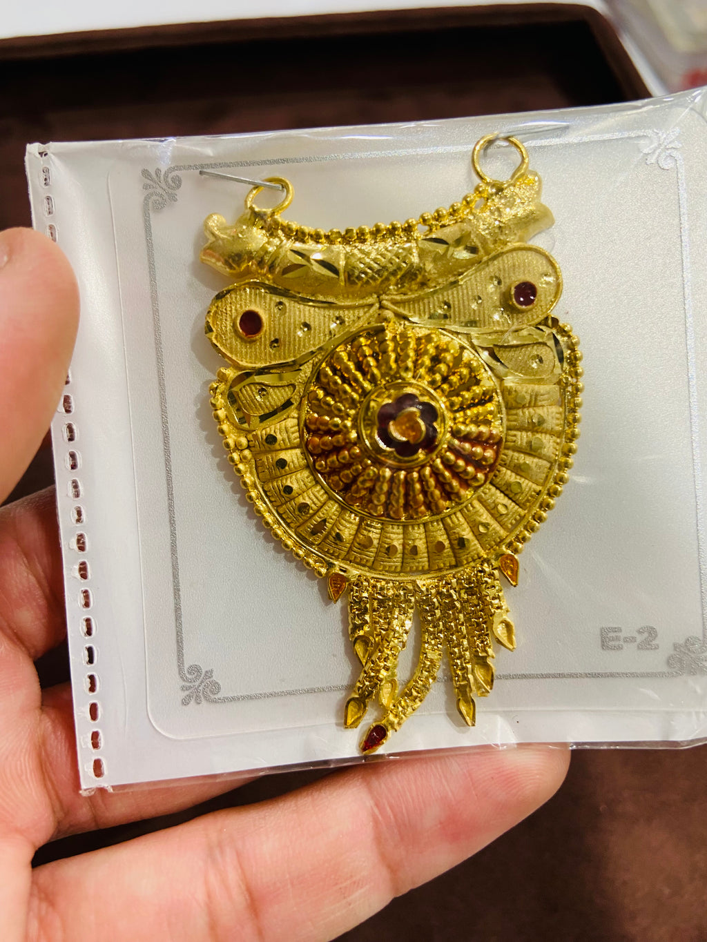 Gold owl-shaped pendant on a card held by a hand