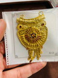 Gold owl-shaped pendant on a card held by a hand