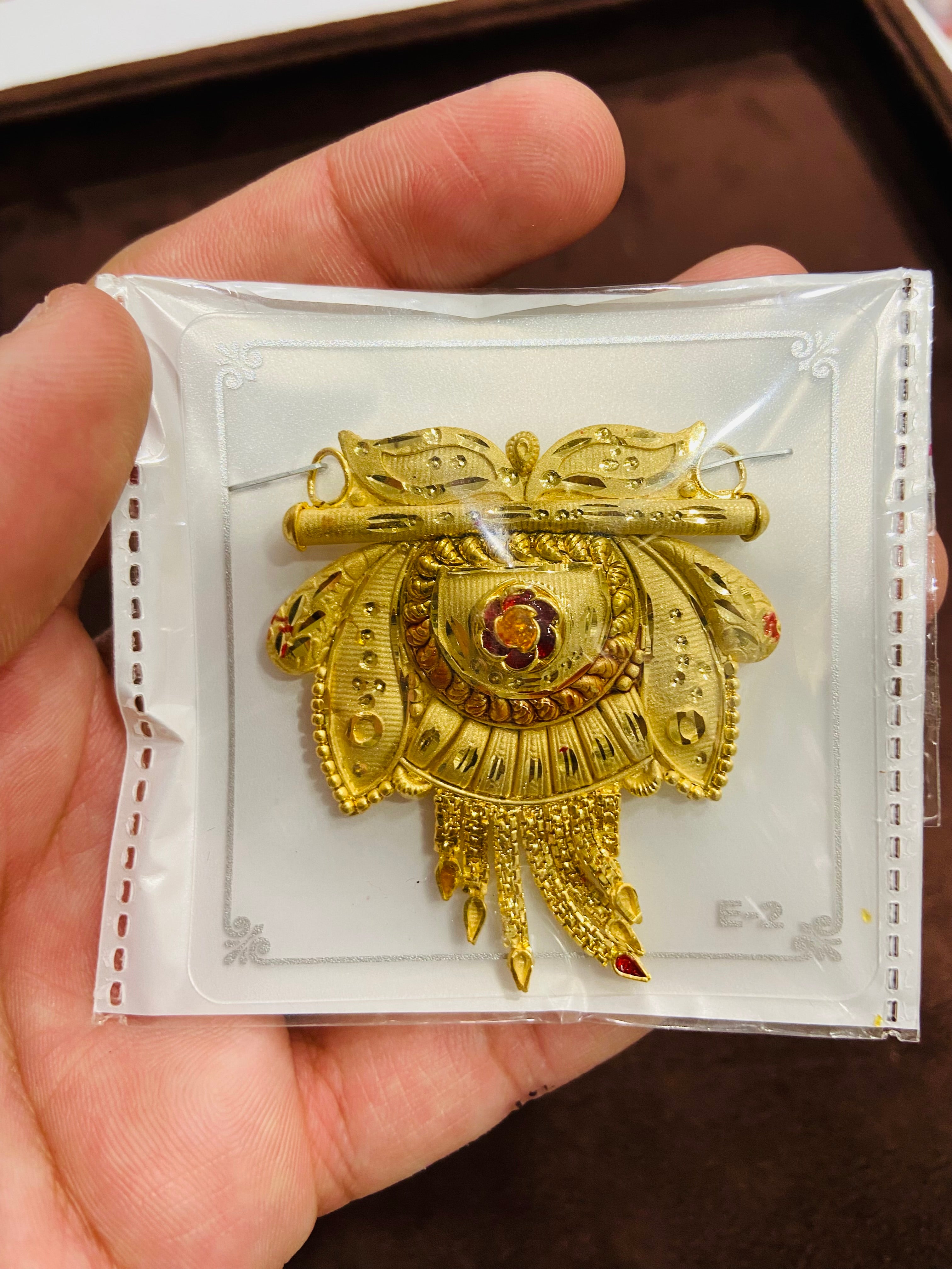 Gold decorative item on a white card held by a hand