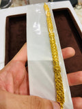 Gold bracelet on a white card held by a hand
