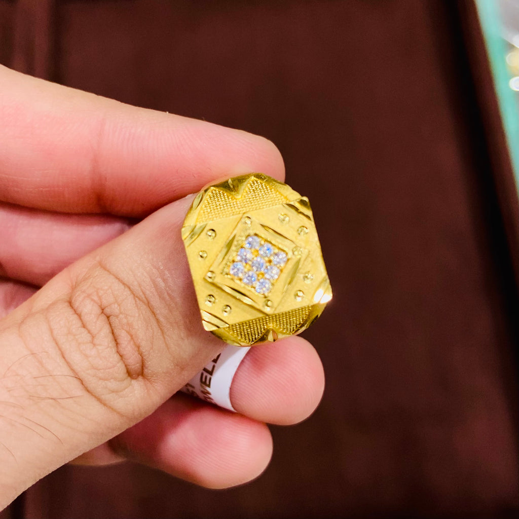 Gold ring with diamond-like stones held between fingers against a blurred background