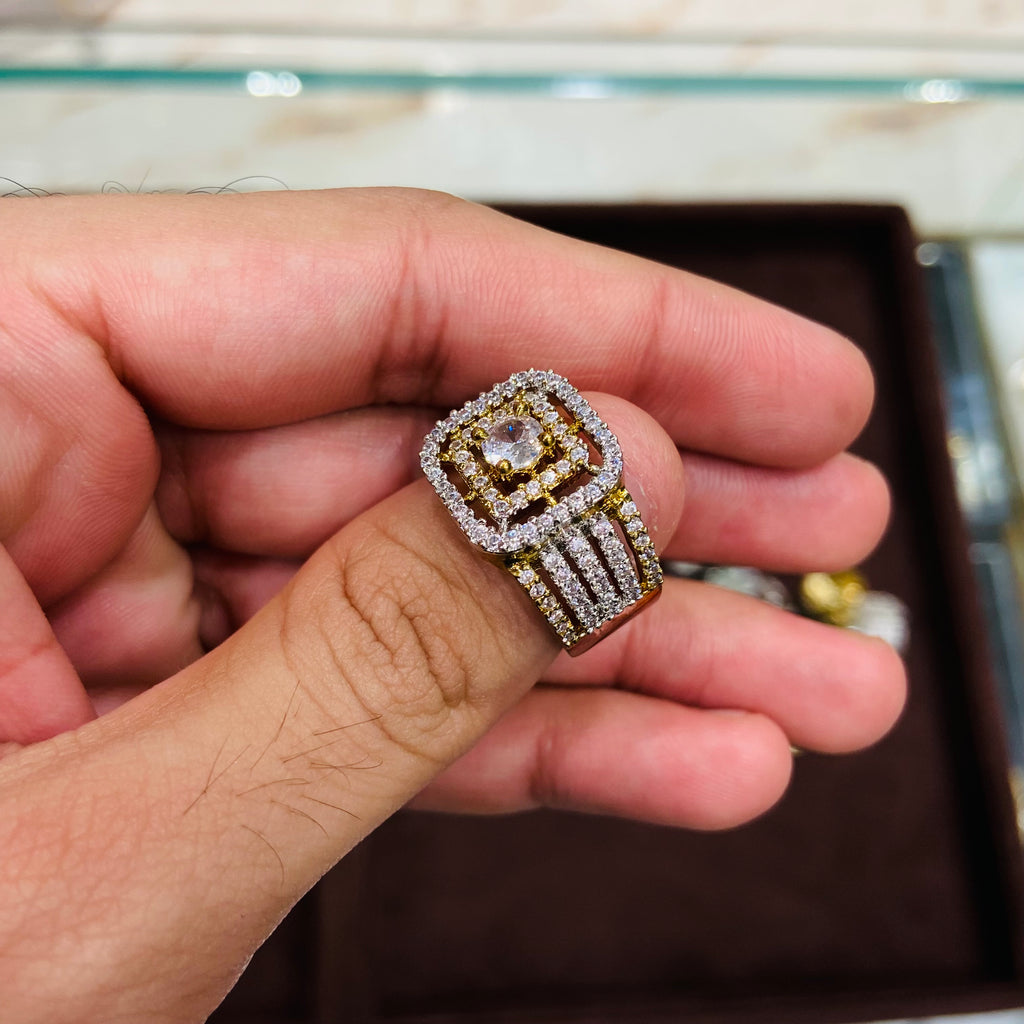 Gold and diamond ring held in a hand with a blurred jewelry box background