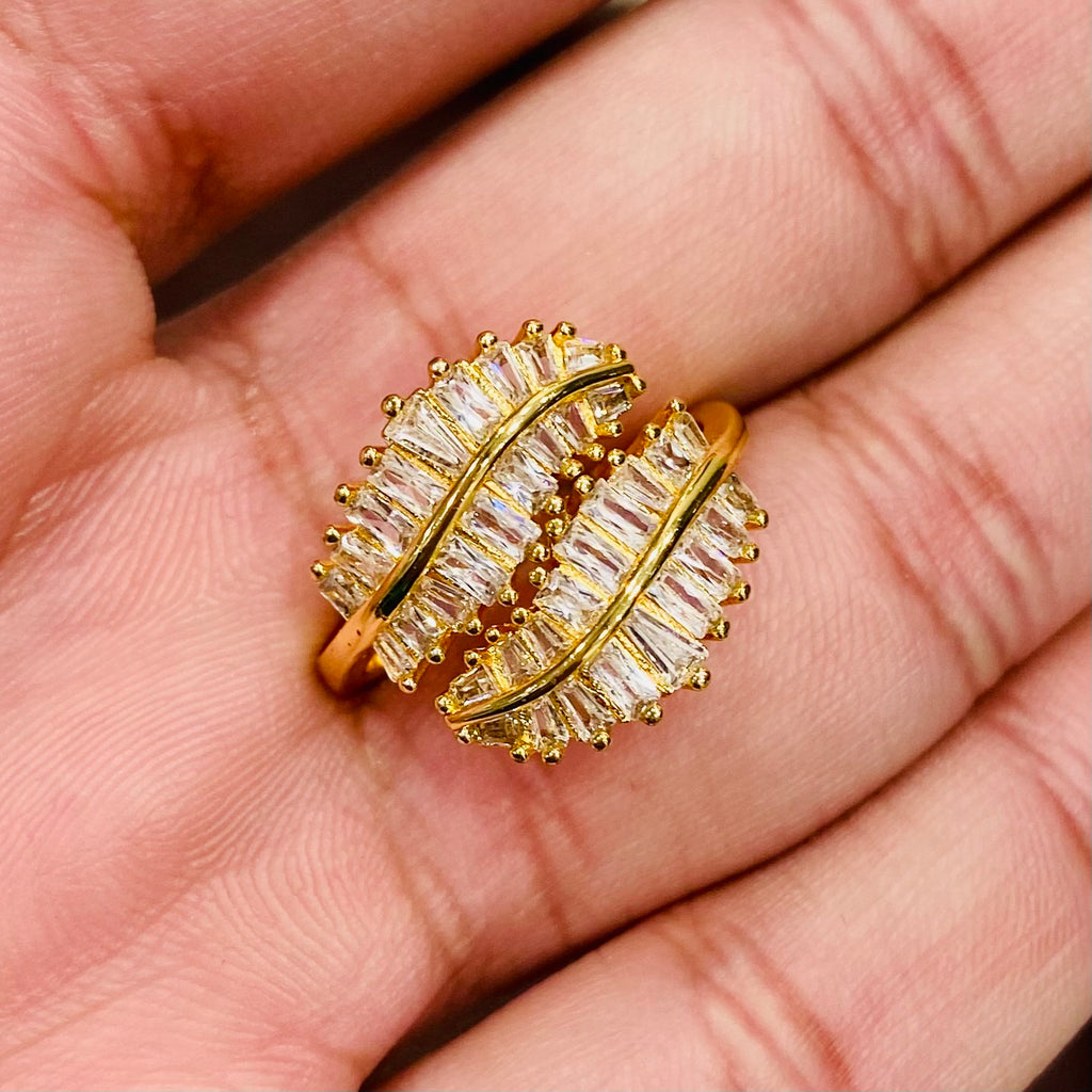 Gold ring with clear gemstones held in a hand
