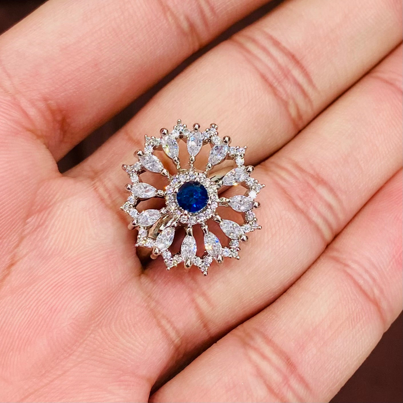 Silver ring with blue gemstone held in a hand